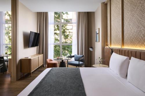 a hotel room with a bed and a chair and window at NH Valencia Center in Valencia