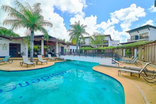 a pool with chairs and palm trees in a house at Hideaway in Paradise in Juan Dolio