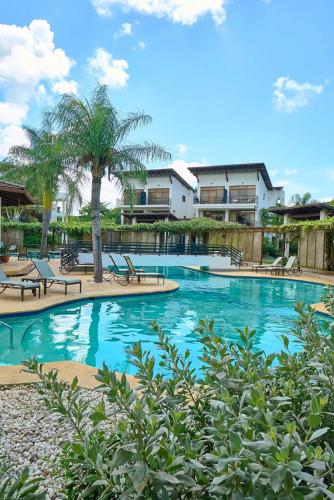a large swimming pool with chairs and a palm tree at Hideaway in Paradise in Juan Dolio
