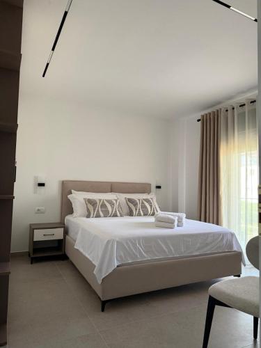 a white bedroom with a large bed and a chair at Vila 18 in Velipojë