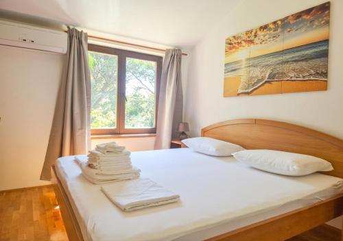 a bedroom with a bed with white sheets and a window at Apartments Mrva in Ugljan