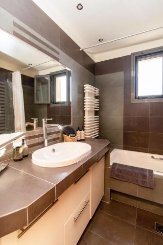 a bathroom with a sink and a tub and a mirror at Azure Villa Kanoni in Análipsis