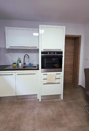 a kitchen with white cabinets and a sink and a stove at Apartma Nad Klancem in Most na Soči