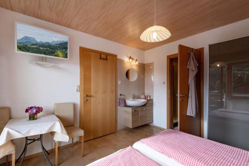 a bedroom with a bed and a bathroom with a sink at Haus Enzian in Thiersee