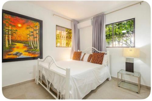 a bedroom with a white bed and a painting on the wall at Villa Donatella Bonao in Bonao