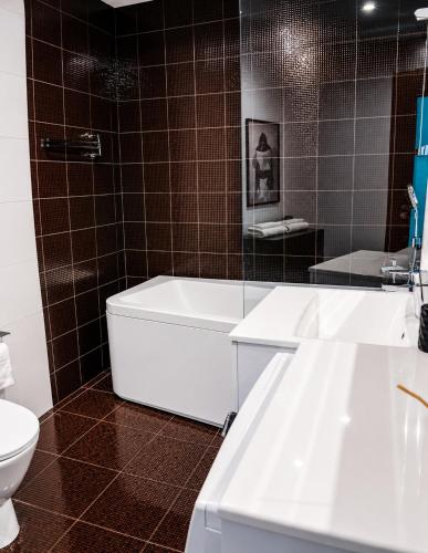 a bathroom with a white tub and a toilet at UP 34 FLOOR APARTMENTS in Klaipėda