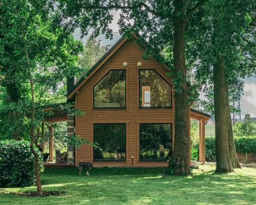 a house with a dog standing in front of it at Domki w Parku in Pępowo