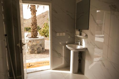 ein Badezimmer mit Toilette, Waschbecken und einer Palme in der Unterkunft ALSARA HiDEAWAY in Qūr