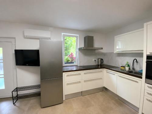 a kitchen with white cabinets and a stainless steel refrigerator at Apartma Nad Klancem in Most na Soči