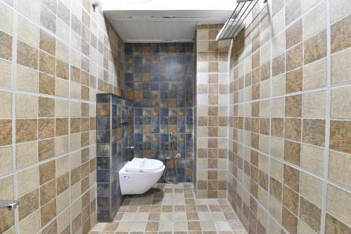 a bathroom with a toilet and a tiled wall at Hotel Pearl Heritage in Jaipur