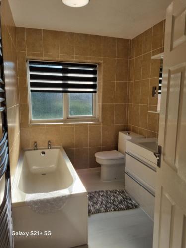 a bathroom with a tub and a toilet and a window at CosyColeby in Nottingham