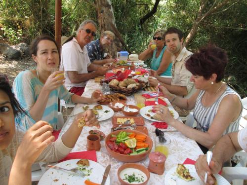 un grupo de personas sentadas alrededor de una mesa comiendo comida en Orna's Corner en Yuval