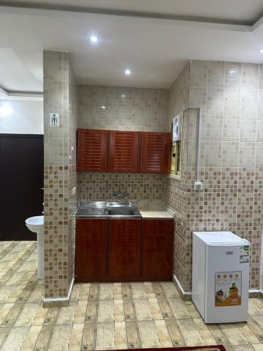 a kitchen with brown cabinets and a sink and a refrigerator at جوهرة عسير in Abha