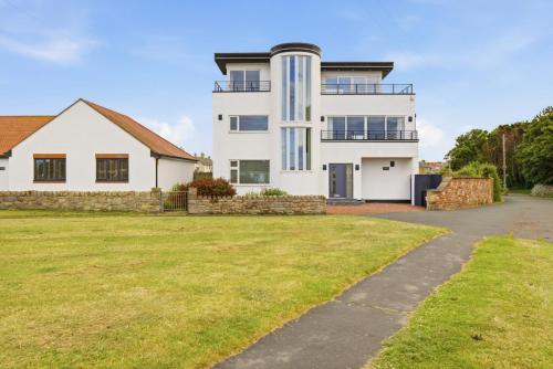 a large white house with a grass yard at Beadnell Point - North East Escapes in Beadnell