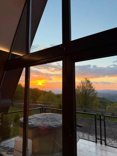 a view of a sunset seen through a window at Klek 77 Luxury Chalets near Jahorina in Paočići