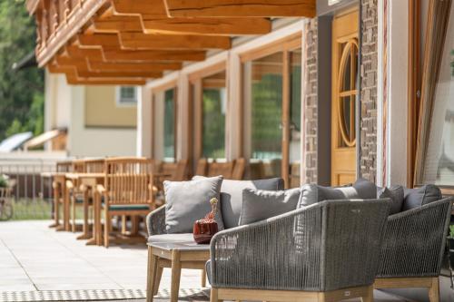 a patio with wicker chairs and a table on a porch at Hotel Schöpf - Mountain Hideaway in Längenfeld