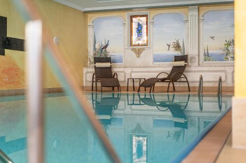 a swimming pool with chairs and a table in a building at Hotel Schöpf - Mountain Hideaway in Längenfeld