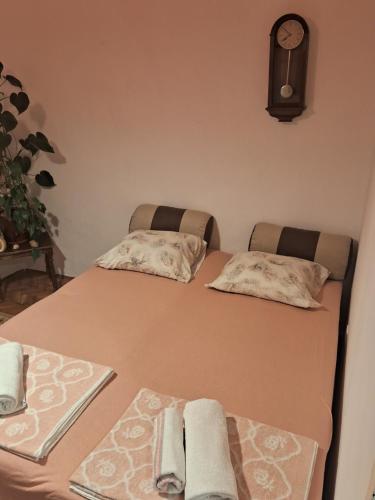 a bed with two pillows and a clock on the wall at Bosiljak in Zelenika