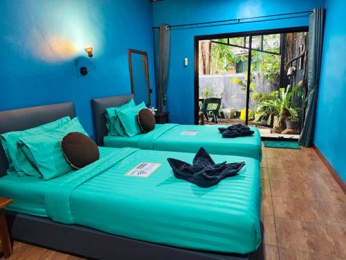 two beds in a room with blue walls at Green Valley Lodge in Khao Sok National Park