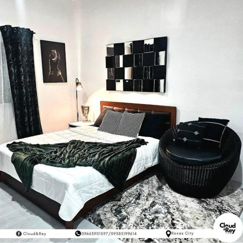 a bedroom with a bed and a black chair at Blanc Suite in Roxas City