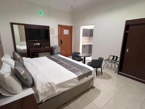 a bedroom with a large bed with a desk and chairs at سرور للشقق المخدومة in Al Baha