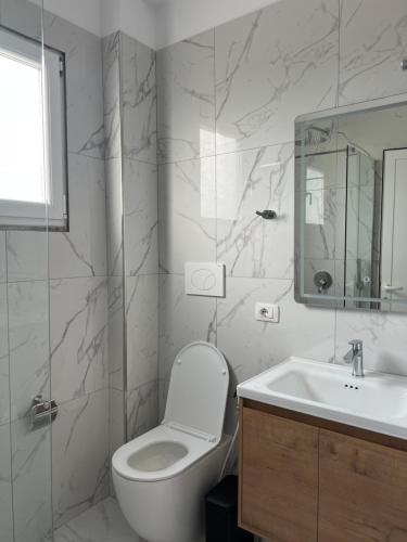 a white bathroom with a toilet and a sink at Velipoja Residences in Velipojë