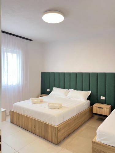 a bedroom with a large bed with a green headboard at Velipoja Residences in Velipojë