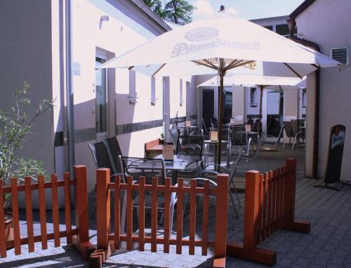 a patio with an umbrella and tables and chairs at Penzion a CaféRestaurant U lávky in Chrudim