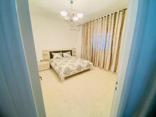 a bedroom with a bed and a chandelier at Appart AL MARAII - Familles seulement in Beni Khiar