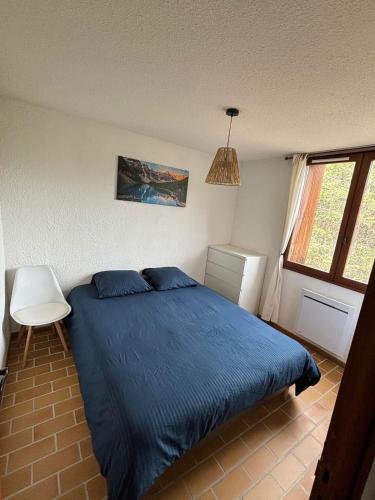 a bedroom with a blue bed and a window at Appartement 2 pièces La Colmiane in La Colmiane
