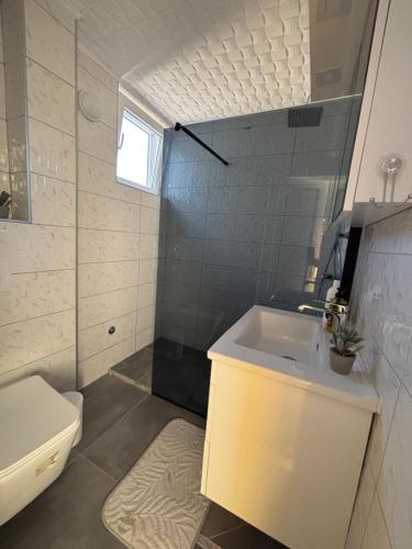 a white bathroom with a sink and a toilet at M apartman in Paraćin