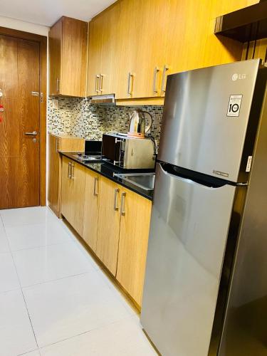 a stainless steel refrigerator in a kitchen with wooden cabinets at Shell Residences Manila by PauL in Manila
