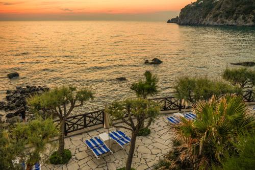 a beach with blue and white chairs and the ocean at Hotel Terme Tritone Resort & Spa in Forio d'Ischia