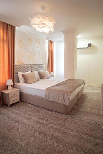 a bedroom with a large bed and a chandelier at Gala Terrace Hotel & Restaurant in Baku