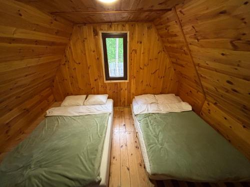 two beds in a log cabin with a window at Rodzinne Zacisze in Radawa