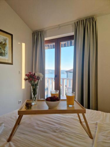 a table with a bowl of fruit on a bed with a window at Dizma Welness Apartmani in Duće