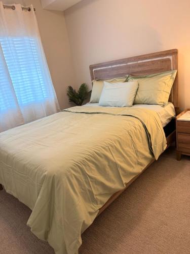 a bedroom with a bed with white sheets and a window at Guest Suite in Langford in Goldstream Station