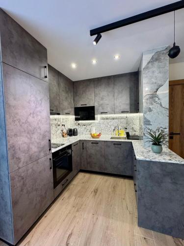 a large kitchen with gray cabinets and wooden floors at Хотел Камъните in Burgas