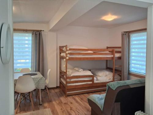 a bedroom with two bunk beds and a table and chairs at Oleandria -,,Domek Jeżynka" nr 30 in Biskupiec