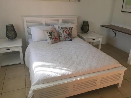 a bedroom with a large bed with two night stands at Hacienda Cooya Beach in Mossman