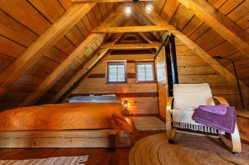 a bedroom in a log cabin with a bed and a chair at Dedekov gaj in Oteš