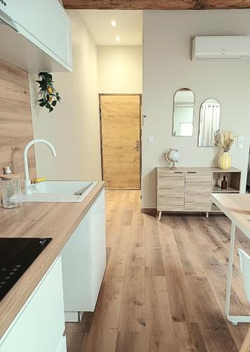 a kitchen with white cabinets and a wooden floor at Studio cosy Le3bis proche Cap d'Agde in Bessan