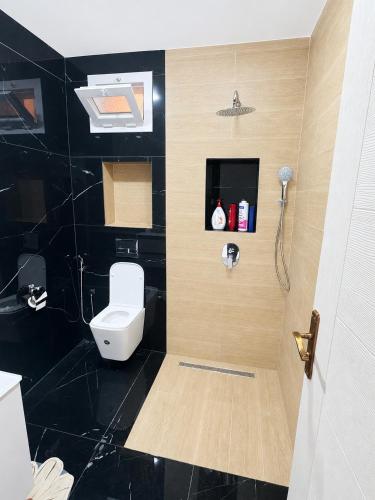 a bathroom with a white toilet and a black wall at Belle appart in Aguemoun Taïda