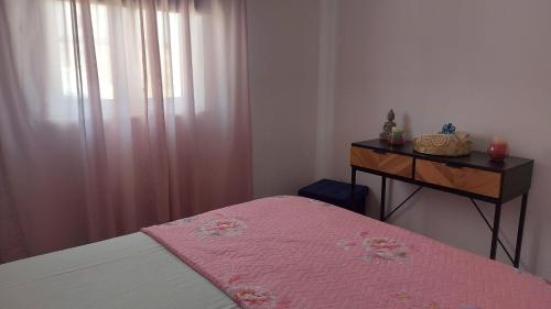 a bedroom with a bed with a pink blanket and a dresser at Casa Alentejana in Mora