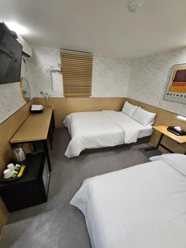 a hotel room with two beds and a desk at T hotel in Seoul
