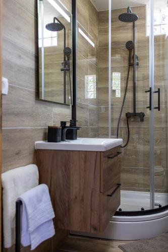 a bathroom with a sink and a shower with a glass door at Holiday House Štrbački buk in Donji Lapac