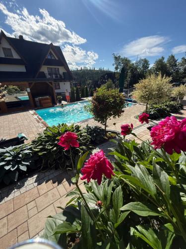 a pool with pink flowers in front of a house at Domek Góralski U Hanki Domek przy Stoku in Małe Ciche