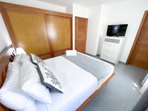 a bedroom with a white bed and a television at Tropicana Suites Deluxe Beach Club & Pool Punta Cana SPA in Punta Cana