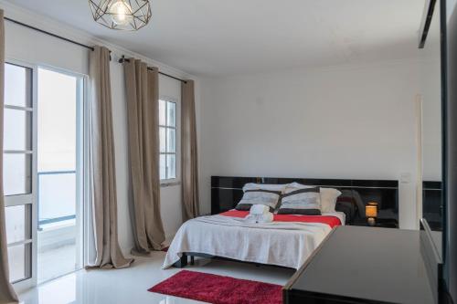 a white bedroom with a bed and a large window at Casa Borboleta in Arco da Calheta