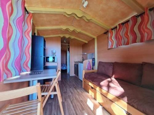a living room with a couch and a kitchen at Comfortable roulotte Chèvres du Vermois in Burthecourt-aux-Chênes